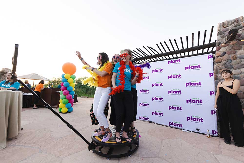Three women pose on a platform at the Consumer Connection photo booth.
